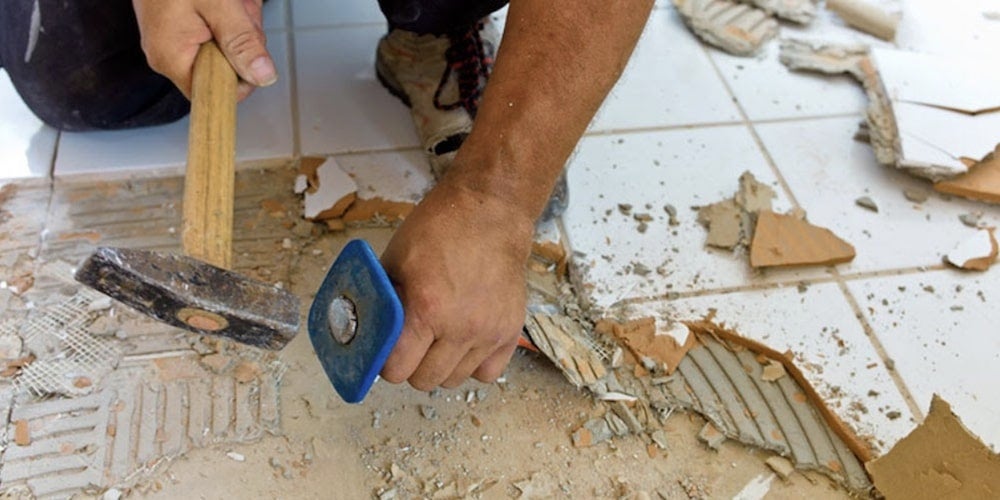 A homeowner tearing up their bathroom tile
