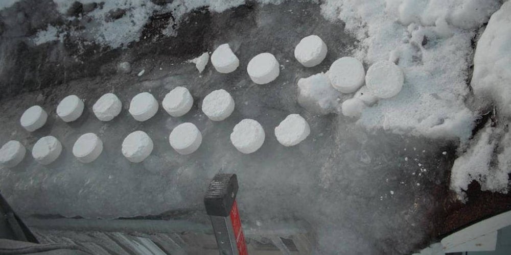 Circles of chemical ice melter sitting on an ice dam