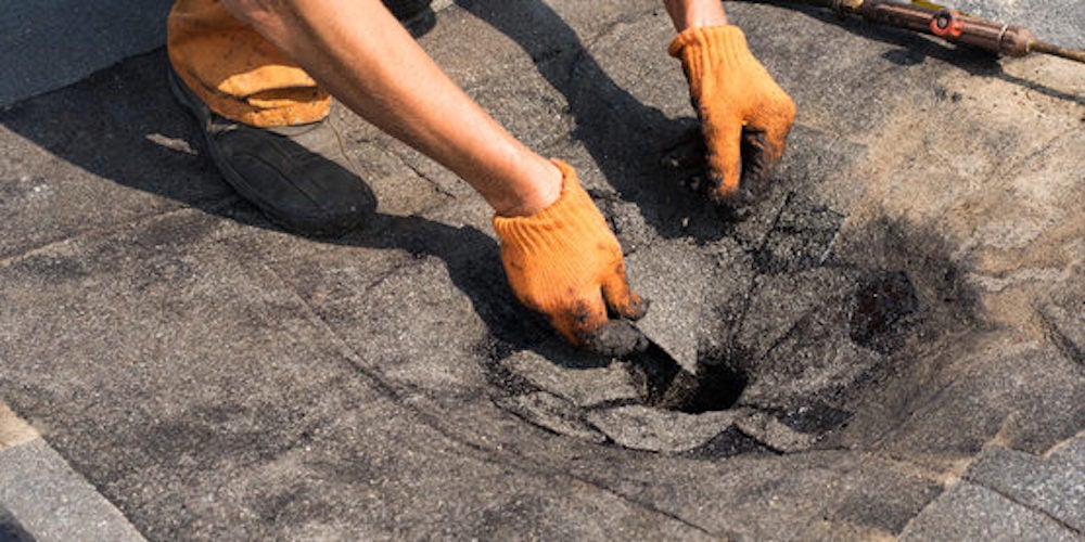 A contractor repairing a flat roof