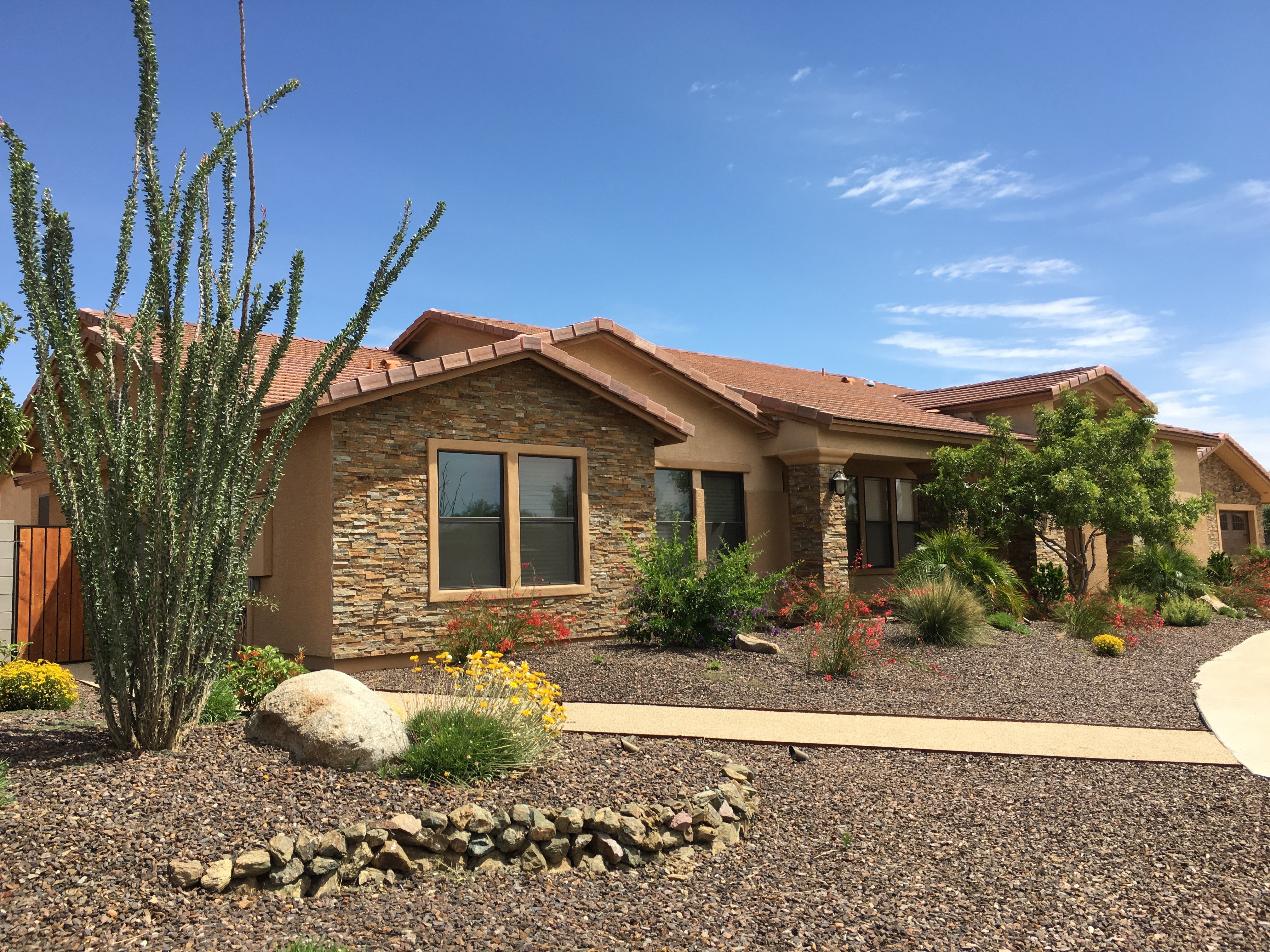 A home in the desert with light brown siding and brown shingles