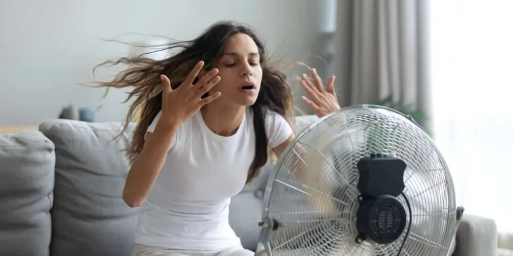 A woman sitting in front of an oscillating fan
