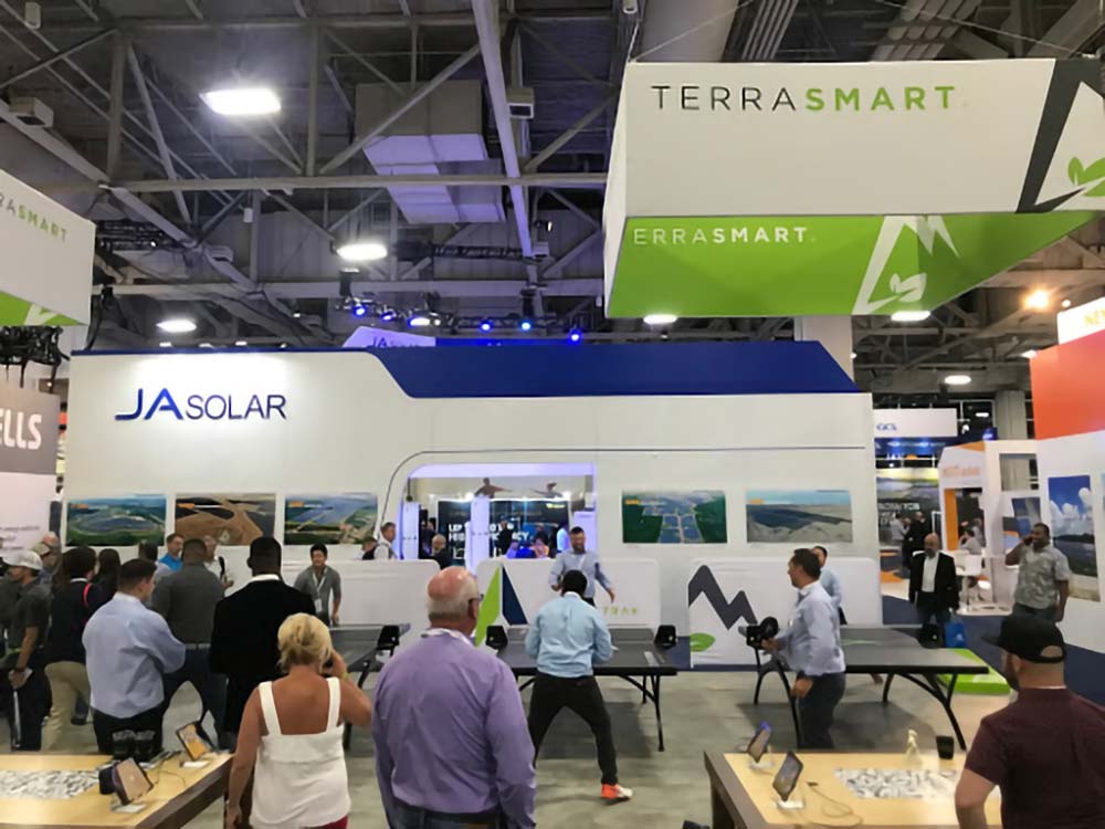 A crowd surrounds three table tennis tables in the Terra Smart booth at SPI2019.