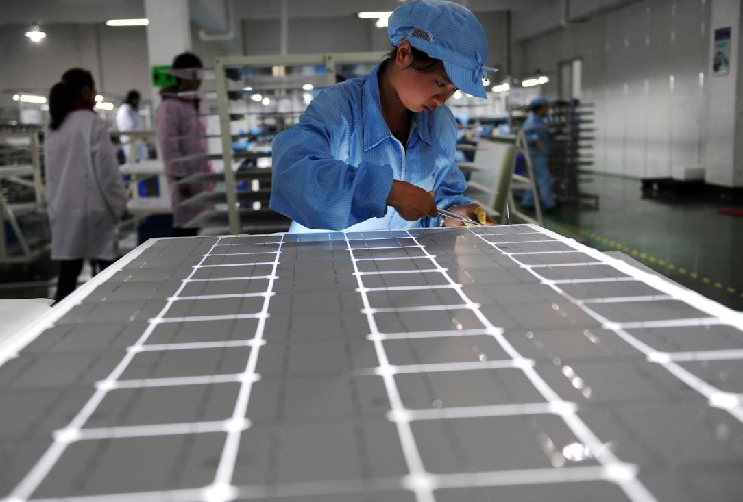  A Chinese worker trims a solar module inside a factory