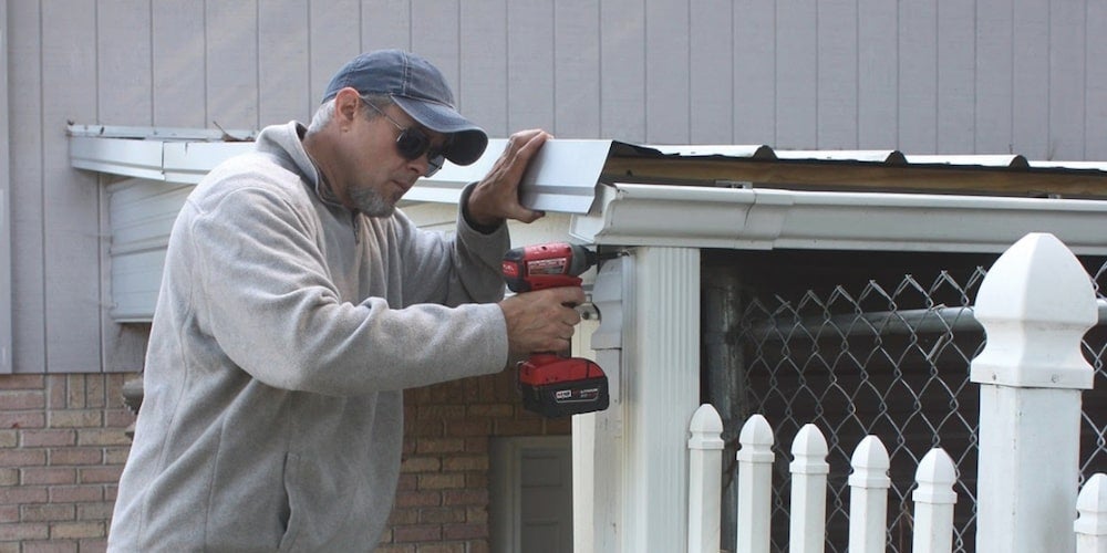A man installing gutters on his home