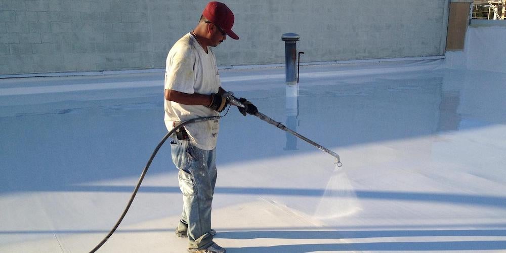 A contractor coating a flat roof