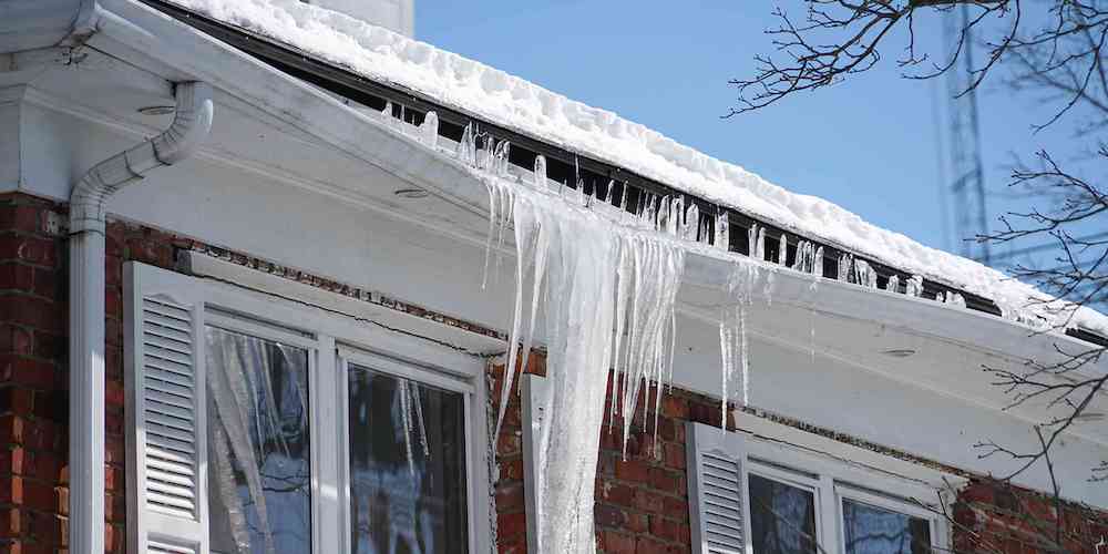 Ice dam on a residential roof damaging the gutters